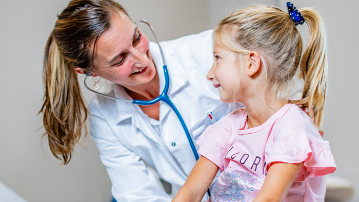 Ärztin mit Stethoskop und blondem Mädchen macht eine pädiatrische Untersuchung im Swiss Medical Network