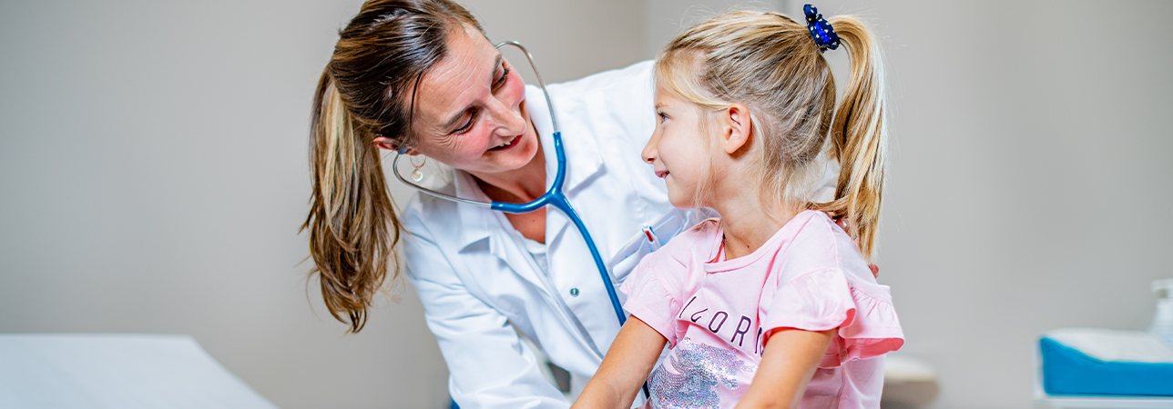 Médecin avec stéthoscope et fillette blonde effectuant un examen pédiatrique au Swiss Medical Network
