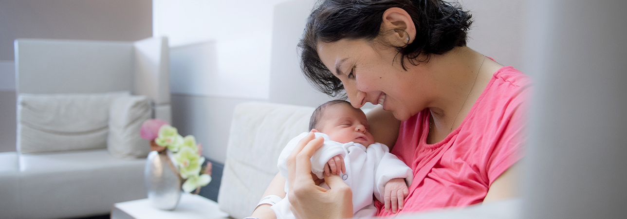 Pregnant woman lovingly holding her baby and smiling